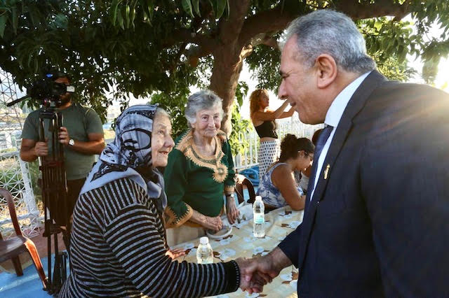 السفير الاسعد مصافحا سيدة فلسطينية من سكان مخيم الضبيه